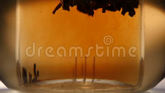 黑叶茶的叶子是用玻璃茶壶冲泡的慢动作视频的预览图