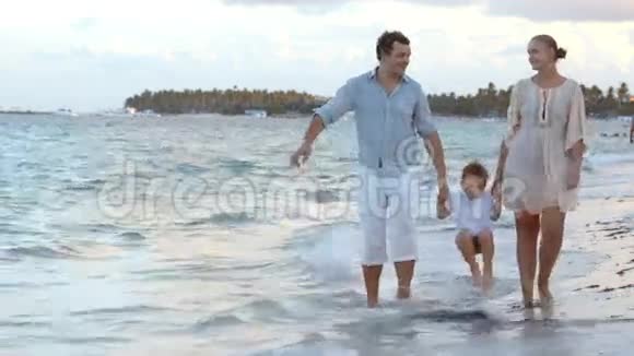 父母和他们的孩子沿着海滩散步视频的预览图