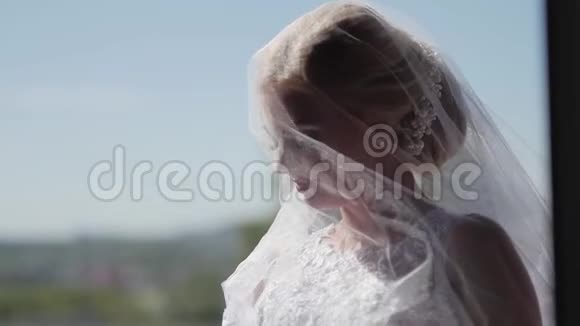 戴着面纱的美丽新娘在窗户附近摆姿势慢动作视频的预览图