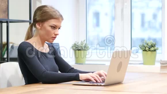 在笔记本电脑上工作的女孩朝镜头微笑视频的预览图