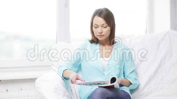 冷静的女人看杂志坐在沙发上视频的预览图