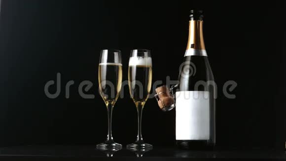 香槟软木塞落在两个长笛和瓶子前面视频的预览图
