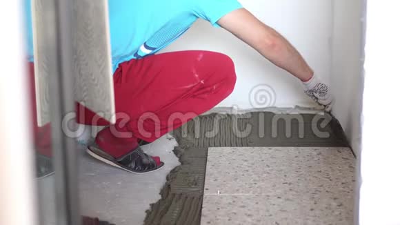 公寓和房屋的修缮和装修专业人员在浴室的地板上铺设瓷砖视频的预览图