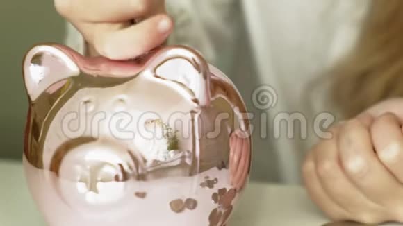 女孩学龄前儿童把钱放在储蓄罐里的粉红猪里视频的预览图
