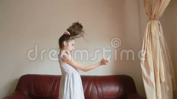 小女孩在家里沙发上用智能手机自拍视频的预览图