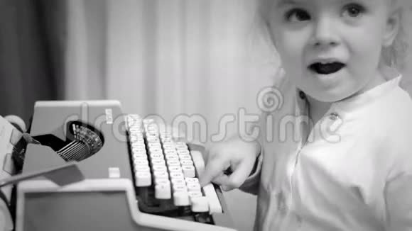 可爱的小女孩在老式打字机上写一本书黑白字体视频的预览图