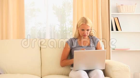 坐在沙发上的女人腿上放着笔记本视频的预览图