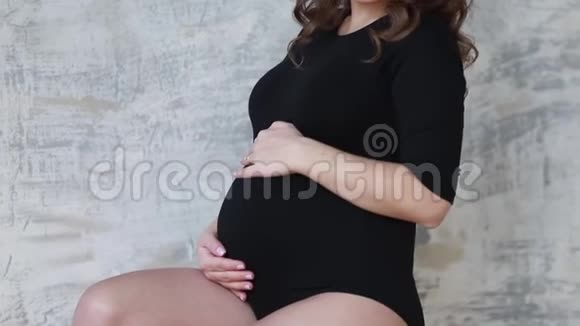 孕妇坐在楼梯上穿着黑色紧身衣的模特她把手放在肚子上未来的母亲视频的预览图