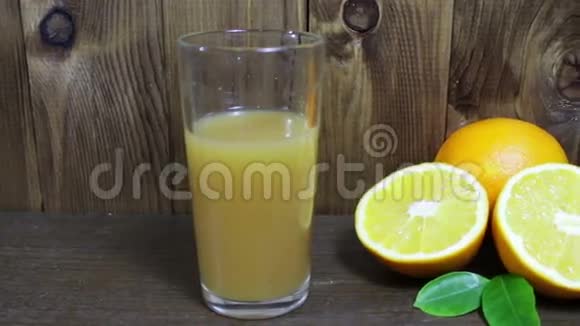 玻璃杯中的橙汁和木制背景的新鲜水果视频的预览图