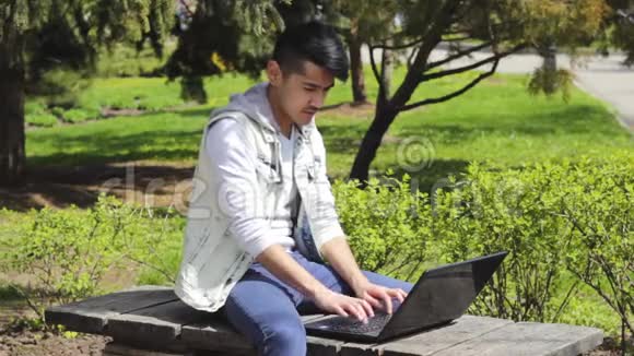 亚洲男子自由职业者在公园里用笔记本电脑工作视频的预览图