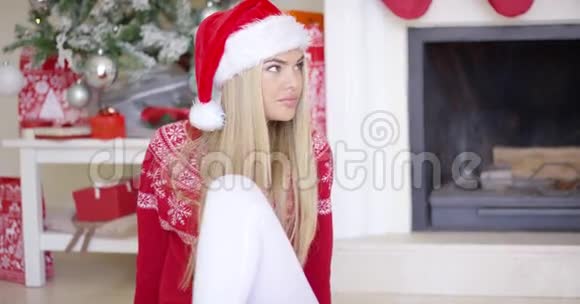 漂亮的年轻女人坐在地板上圣诞树后面视频的预览图