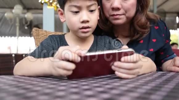 快乐的亚裔男孩和他妈妈玩智能手机游戏视频的预览图