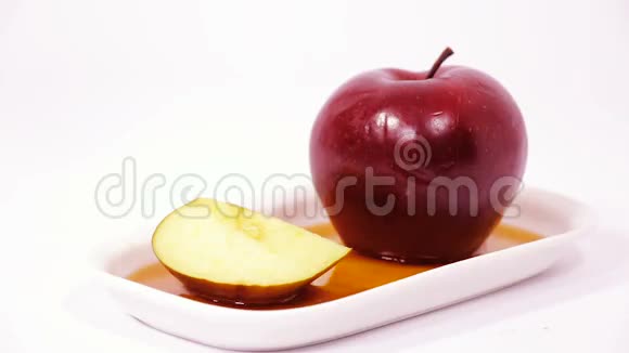 将蜂蜜倒入红苹果上将红苹果切片在白色背景上分离蜂蜜视频的预览图