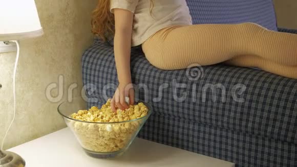 一个小女孩坐在沙发上看电视吃爆米花视频的预览图