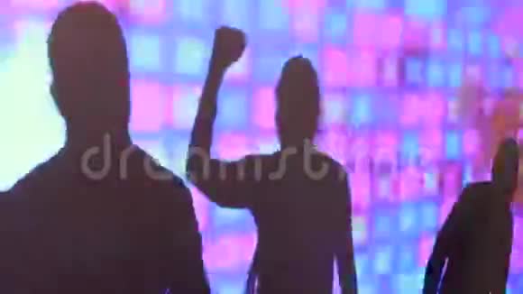 派对期间在夜总会的彩屏上跳舞的男女剪影视频的预览图