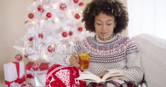 在圣诞树前看书的女人视频的预览图