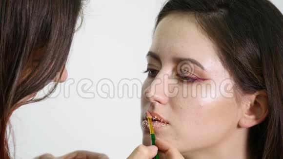化妆师把纸屑放在嘴唇上嘴唇上的纸屑美丽的妆容和明亮的嘴唇颜色视频的预览图