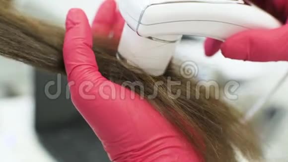 皮肤科医生诊断一个年轻漂亮女孩的头发结构与一个特殊的工具一个旋毛镜视频的预览图