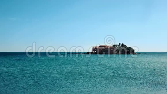 小岛上有一座房子周围是平静而温和的绿松石海笼罩着夏天的蓝天视频的预览图