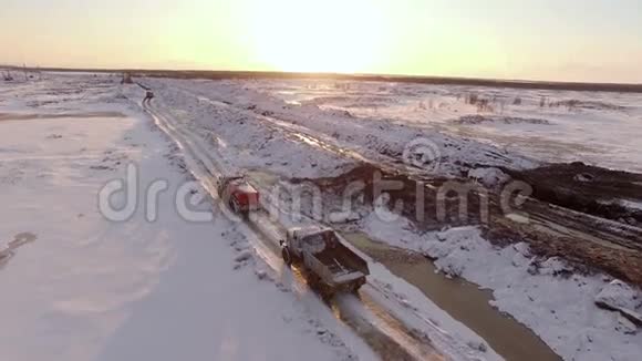 在积雪覆盖的冬季道路上行驶的车辆的空中日落景色视频的预览图