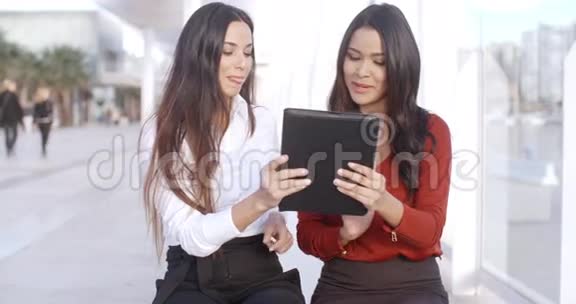 两个女人在讨论平板电脑上的信息视频的预览图