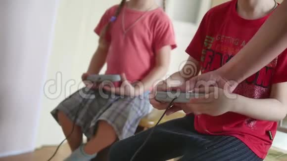 孩子们在室内控制台上玩电子游戏男孩和女孩在网上玩游戏视频的预览图