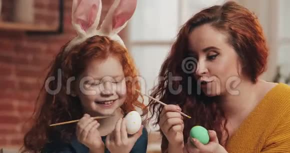 复活节快乐妈妈和她的小女儿画鸡蛋为复活节做准备的幸福家庭他们戴着兔子耳朵视频的预览图