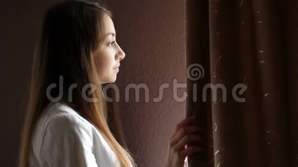 美丽的年轻女子望着窗外视频的预览图
