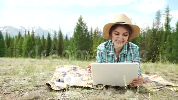 一个漂亮的棕色女孩在荒地上用平板电脑视频的预览图