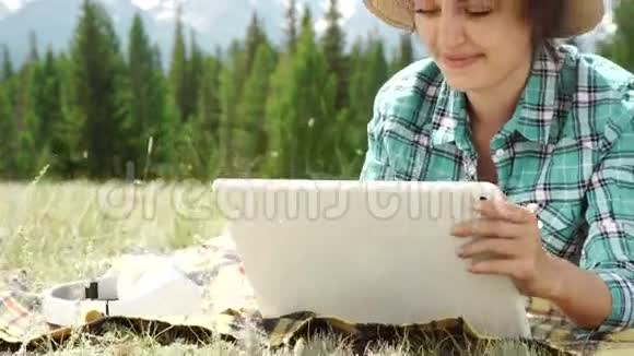 一个漂亮的棕色女孩在荒地上用平板电脑视频的预览图