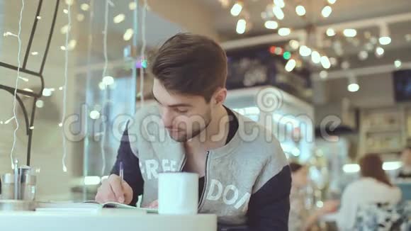 年轻人在咖啡馆里写记事本视频的预览图