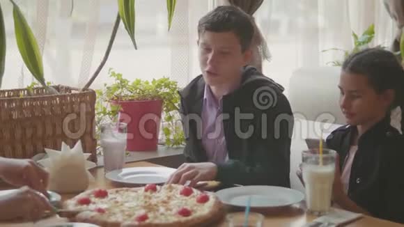 男孩和女孩在咖啡厅慢动作视频中吃披萨孩子们吃比萨饼吃美味的比萨饼朋友的陪伴视频的预览图
