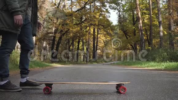 一个人骑着长板溜冰在穿过森林的道路上视频的预览图