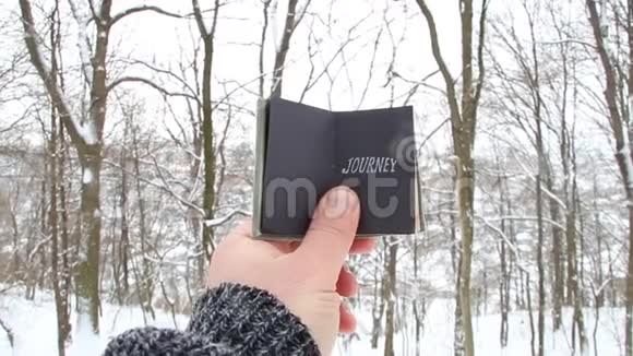 乔尼概念手拿着一本有铭文的书冬季森林的背景视频的预览图