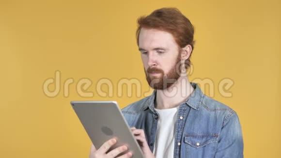 红发男子在平板电脑上浏览互联网视频的预览图