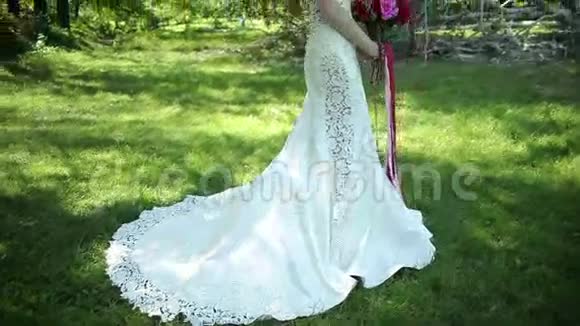 带火车的婚纱美丽的婚礼花束在年轻新娘手中婚礼公园里的年轻女子视频的预览图