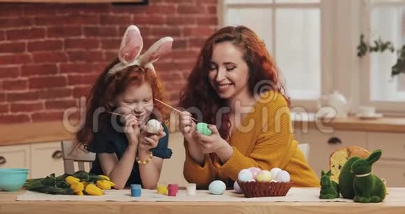 复活节快乐妈妈和她的小女儿画鸡蛋为复活节做准备的幸福家庭他们戴着兔子耳朵视频的预览图