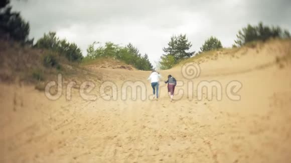 这位母亲穿着雨衣和儿子玩耍在海滩上跑下海视频的预览图