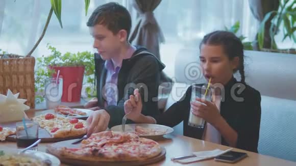 男孩和女孩在咖啡厅慢动作视频中吃披萨孩子们吃比萨饼吃美味的比萨饼朋友的陪伴视频的预览图