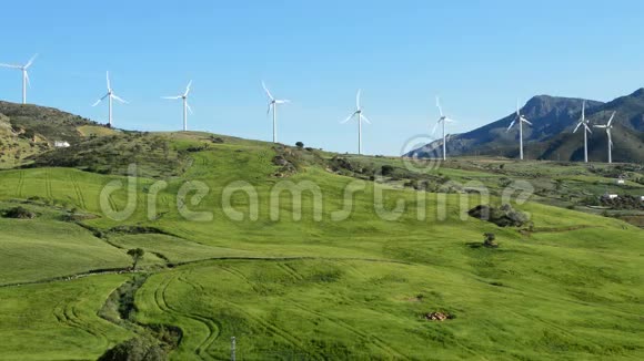 风力涡轮机的景观能量在阳光明媚的日子里一起在田野道路和山脉中移动视频的预览图
