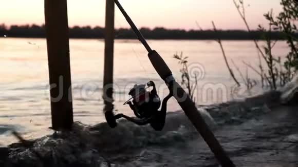 鱼竿与卷筒等待咬在背景黄昏日落在河流视频的预览图