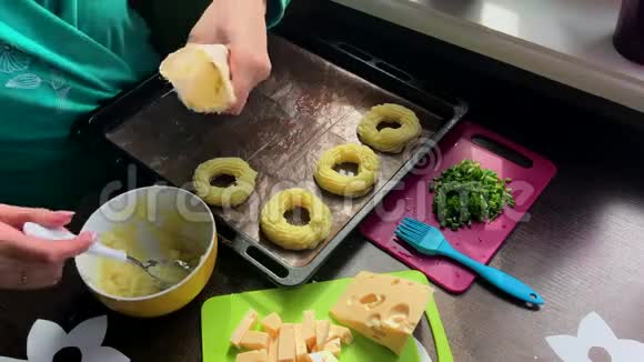 一个女人用土豆泥装满了糕点袋奶酪洋葱片和炸蘑菇在盘子里视频的预览图