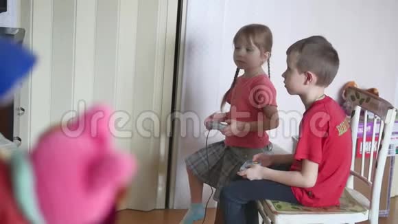 孩子们玩电子游戏控制台男孩和女孩在室内玩网络游戏视频的预览图
