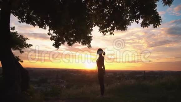 一位女子在美丽的日出练习瑜伽的剪影视频的预览图