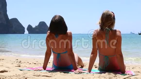 年轻的黑发女孩和金发女孩坐在浴巾上视频的预览图