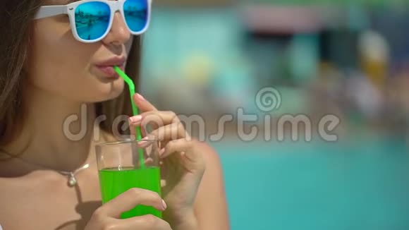 夏天美丽的年轻女子比基尼女孩在热带游泳池放松喝鸡尾酒的女人这就是视频的预览图