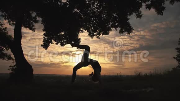 一位女子在美丽的日出练习瑜伽的剪影视频的预览图
