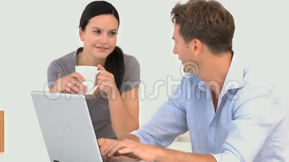 一对夫妇围着他们的笔记本电脑说话视频的预览图