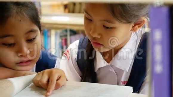 穿制服的亚洲小学生在图书馆看书视频的预览图