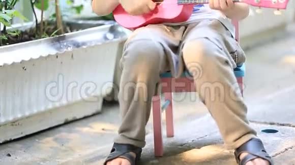 小亚洲小孩坐在迷你椅子上弹吉他视频的预览图